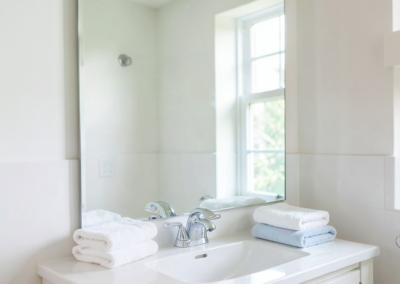 Bright bathroom vanity with a polished mirror, clean sink basin, and folded towels after professional residential cleaning.