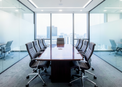 Conference room with a polished table, aligned chairs, and streak-free glass walls after commercial cleaning.