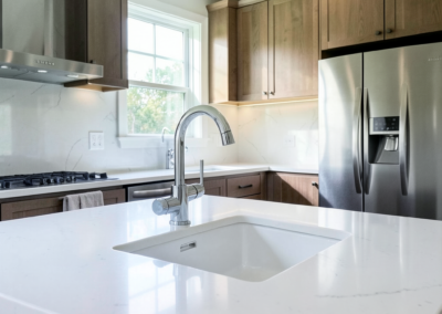 Spotless kitchen with gleaming quartz counters, polished faucet, and streak-free stainless appliances after a deep residential clean.